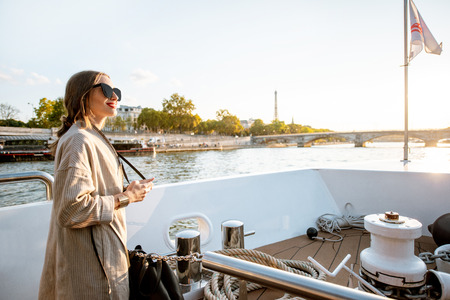 Young woman enjoying beautiful landscape view on the riverside from the ship during the sunset in Parisの写真素材