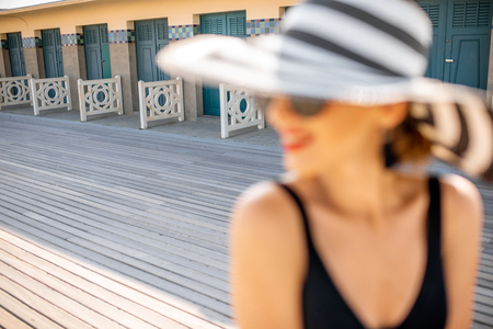 Portrait of a beautiful woman in striped hat on the beach near the old locker rooms in Deauville, famous french resort in Normandy. Woman is out of focusの写真素材