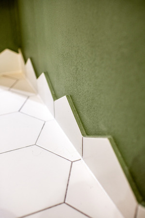 Close-up of the floor corner made with hexagonal white tiles and green walllの写真素材