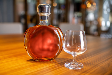 Bottle of the cognac with empty glass on the table in cigar roomの写真素材