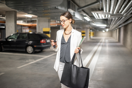 Young business woman walking with car keys in the underground parking of the new residential buildingの写真素材