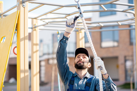 Handsome workman in uniform mounting rope for climbing on the playground outdoorsの写真素材