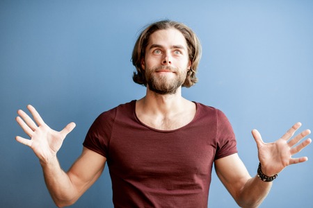 Portrait of a young caucasian bearded man with long hair dressed in t-shirt on the colorful backgroundの写真素材