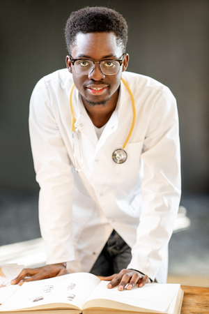 Portrait of a young african ethnicity physician or medical student in uniform during the work or study in the office or classroomの写真素材