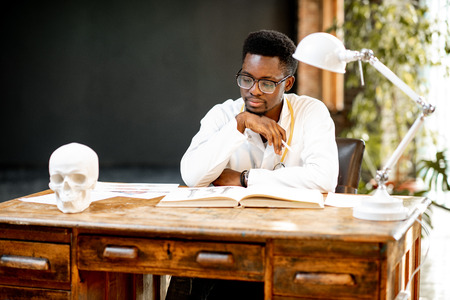 Portrait of a young african ethnicity physician or medical student in uniform during the work or study in the office or classroomの写真素材