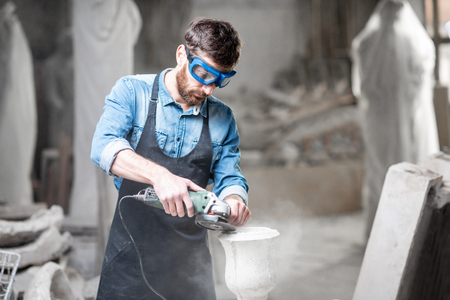Sculptor in workware grinding stone vase at the working space in the old atmospheric studioの写真素材