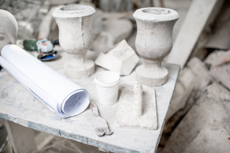 Working place with old sculptures, working tools and drawings on the table in the sculptors studioの写真素材