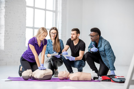 Group of young people learning to make artificial breathing with medical dummies during the first aid training in the white roomの写真素材