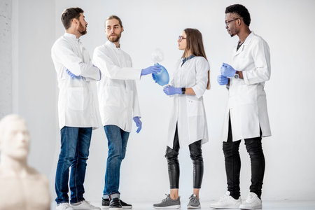 Group of young medics standing and talking together during the break of the first aid training with...