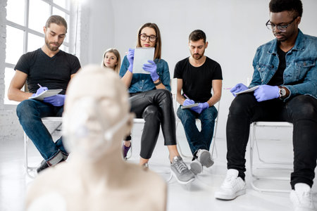 Group of young people sitting and writing during the medical first aid training in the white...