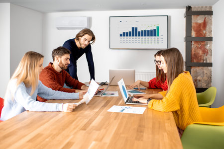 Coworkers dressed casually sitting together during the meeting in the boardroom with some charts and...