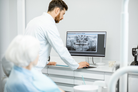 Dentist showing panoramic shot of the jaw on the computer to the elder woman during the consultation in the dental officeの写真素材