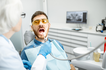 Handsome man during the medical examination with elderly woman dentist in the dental officeの写真素材