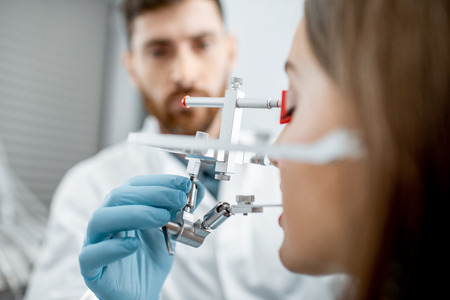 Dentist putting jaw measurement system to a young woman patient in the dental office, close-up viewの写真素材