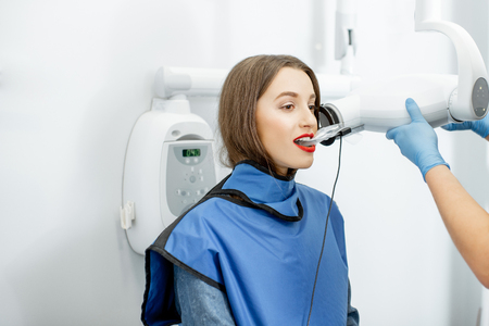 Young woman in protective wear making x--ray shot of a tooth in the dental officeの写真素材