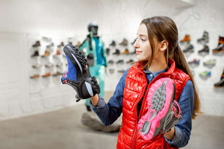 Young woman choosing trail shoes for mountain hiking in the modern sports shopの写真素材