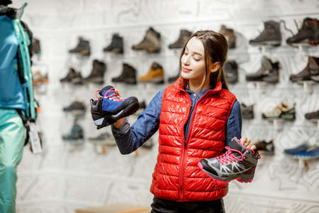 Young woman choosing trail shoes for mountain hiking in the modern sports shopの写真素材
