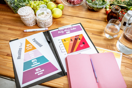 Nutritionists working place with drawings on the topic of healthy eating, empty notebook and different products on the tableの写真素材