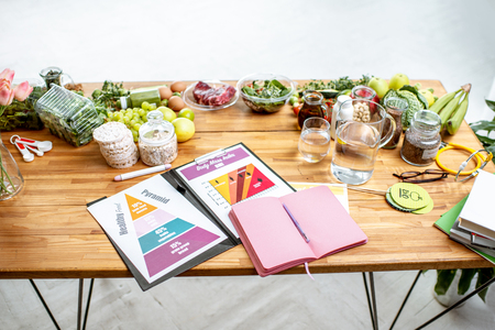 Nutritionists working place with drawings on the topic of healthy eating, empty notebook and different products on the tableの写真素材