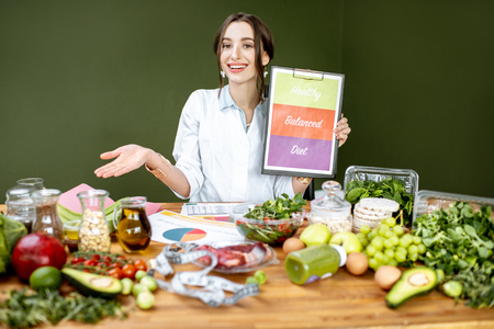 Dietitian promoting healthy balanced eating sitting at the table full of variuos productsの写真素材