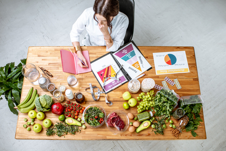 Dietitian writing diet plan, view from above on the table with different healthy products and drawings on the topic of healthy eatingの写真素材