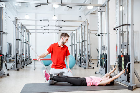 Young girl exercising on the decompression simulators with trainer during the spine treatment at the...