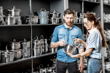 Young couple choosing pans for cooking in the department with kitchen utensils at the supermarketの写真素材