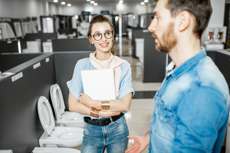 Young couple choosing lavatory pan standing together in the building shop with sanitary ceramicsの写真素材
