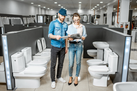 Young couple choosing lavatory pan standing together in the building shop with sanitary ceramicsの写真素材