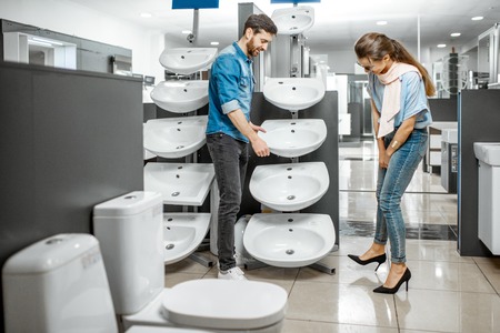 Young couple choosing new bathroom sink at the plumbing shop with lots of sanitary goodsの写真素材