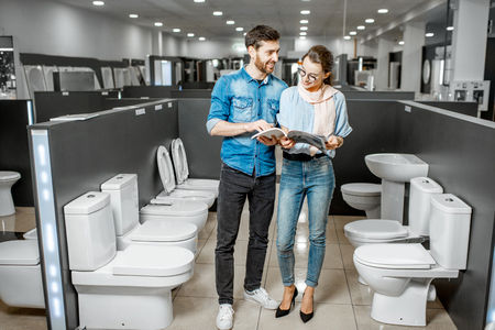 Young couple choosing lavatory pan standing together in the building shop with sanitary ceramicsの写真素材