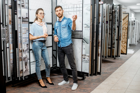 Beautiful young couple choosing ceramic tiles for their house repairment in the building shopの写真素材