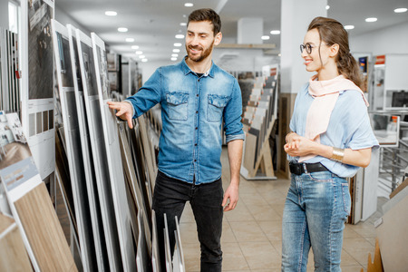 Beautiful young couple choosing ceramic tiles for their house repairment in the building shopの写真素材