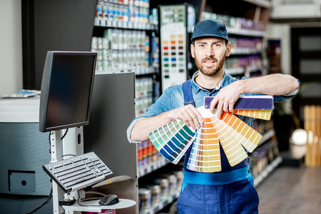 Portrait of a handsome workman with color swatches near the equipment for coloring in the building shopの写真素材