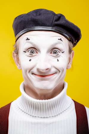 Close-up portrait of an actor as a pantomime with white facial makeup showing expressive emotions on the yellow background indoorsの写真素材