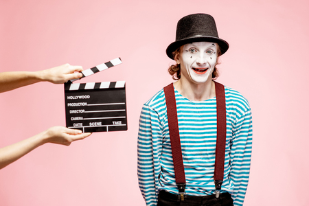Portrait of an actor as a pantomime with cinematography clapperboard on the pink backgroundの写真素材