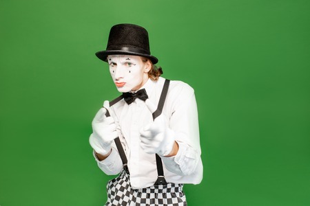 Portrait of an actor as a pantomime with white facial makeup posing with expressive emotions isolated on the green backgroundの写真素材