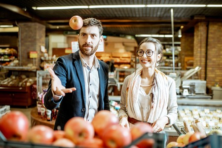 Young couple choosing apples while buying food in the supermarketの写真素材