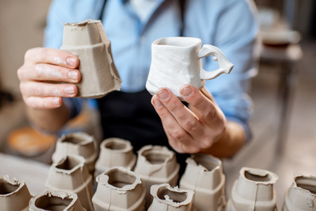 Potter holding ceramic workpieces in the pottery, close-up viewの写真素材