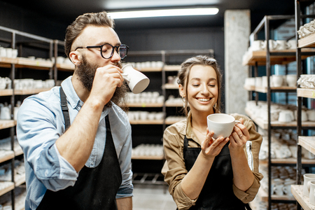 Man and woman workers checking quality of the clay products during the drying process at the potteryの写真素材