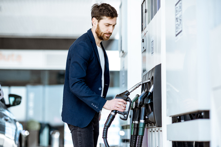 Businessman refueling his luxury car holding filling gun at the gas stationの写真素材