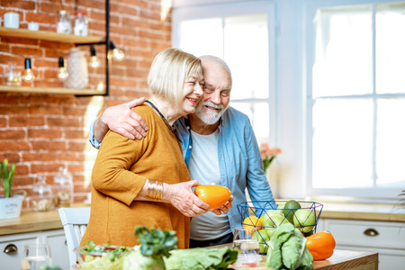 Cheerful senior couple cooking food with healthy fresh ingredients on the kitchen at home. Concept of healthy nutrition in older ageの写真素材