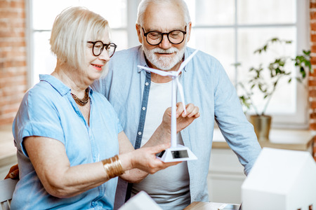 Portrait of a senior couple playing with toy wind turbine, dreaming about an alternative source of energyの写真素材