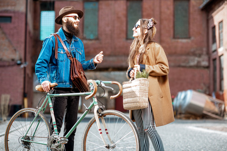 Stylish young man and woman having a conversation standing together with retro bicycle outdoors on the industrial urban backgroundの写真素材