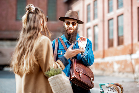 Stylish young man and woman having a conversation standing together with retro bicycle outdoors on the industrial urban backgroundの写真素材