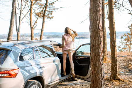 Young woman traveler enjoying nature while traveling by car in the picturesquare forest with lakeの写真素材