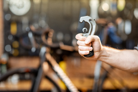 Repairman holding tube cutter for bicycle helm in the workshop, close-up viewの写真素材