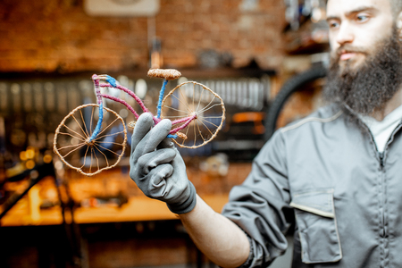 Repairman holding a small toy bicycle at the bicycle workshopの写真素材
