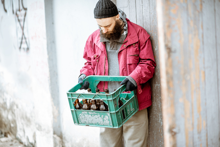 Homeless beggar bringing box with glass bottles to the collection point. Way of earning money for the poorの写真素材