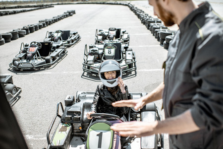 Man instructing young woman driver, explaining the rules before racing on the go-karts on the track outdoorsの写真素材